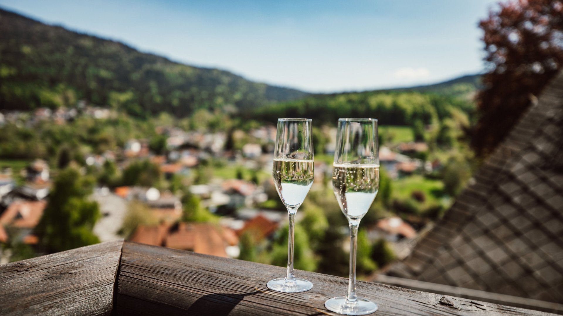 Wellnesshotel im Bayerischen Wald - Das Hotel Hofbräuhaus Zwei Sektgläser auf dem Balkon mit Panoramablick über Bodenmais und den Bayerischen Wald – Genussmoment im Wellnesshotel Hofbräuhaus