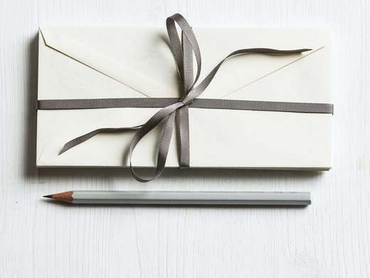 Ihr Traumurlaub im Hotel Hofbräuhaus Bleistift und Kuvert mit Schleife auf heller Oberfläche – stilvolle Geschenkidee oder Einladung, minimalistisch arrangiert