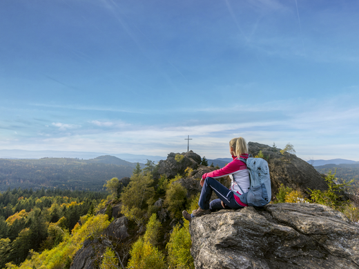 Wandern in Bodenmais: unsere Tipps Wanderin genießt Panoramablick vom Silberberg-Gipfel mit Gipfelkreuz im Bayerischen Wald – Ausflugstipp nahe Wellnesshotel Hofbräuhaus Bodenmais